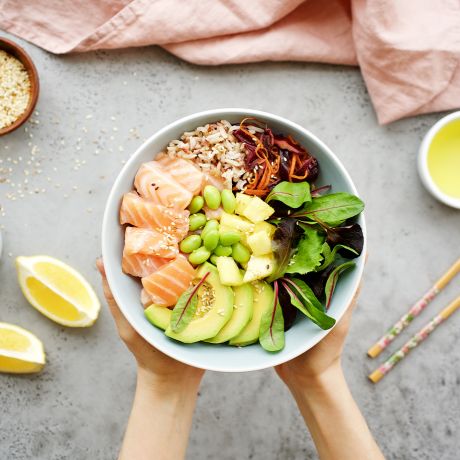 Mani che tengono una ciotola bianca con Poké Bowl