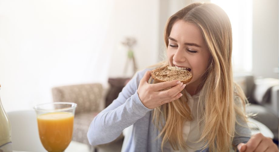 Ragazza che mangia una fetta di pane integrale