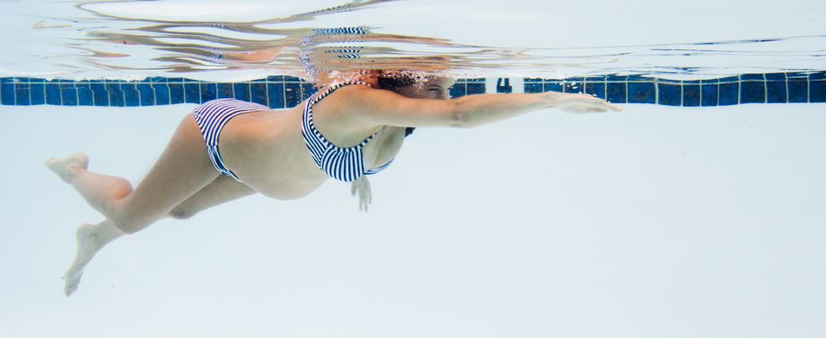 donna incinta che nuota in piscina