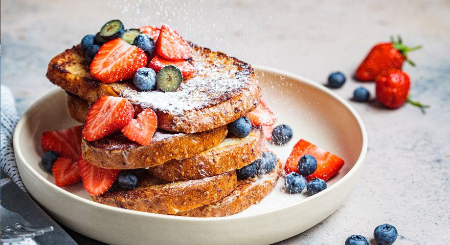 Dessert con pane raffermo, fragole e mirtilli su piatto bianco